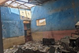 Image showing a classroom with debris scattered across the room as a result of recent conflict.